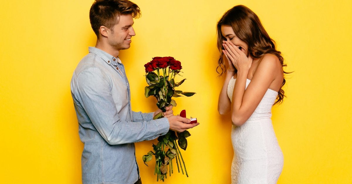 Man with engagement ring and roses making proposition of marriage his girlfriend