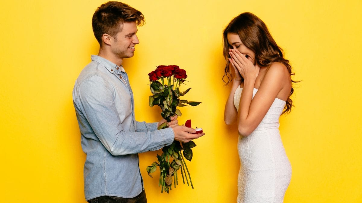 Man with engagement ring and roses making proposition of marriage his girlfriend