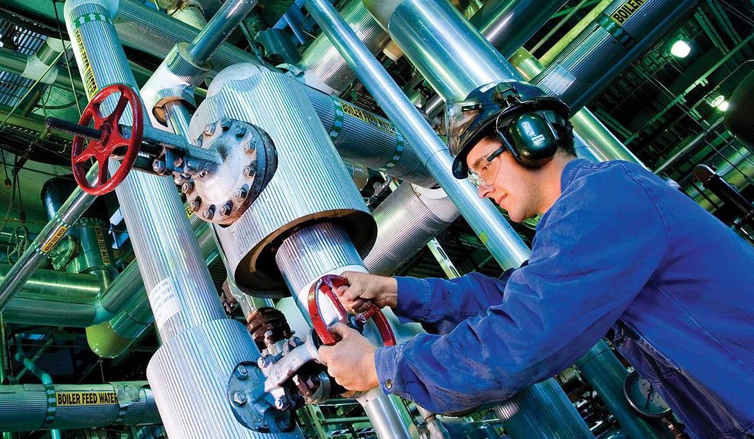 Man wearing safety gear, fixing a pipe